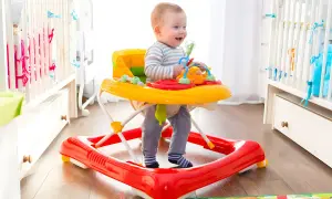 Glad bebis i en färgglad gåstol utforskar rummet.