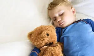 En liten pojke sover sött med sin nallebjörn. Kanske är det dags att sluta sova på dagen och vara vaken istället.