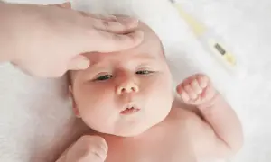 En hand känner på ett barns panna. Bredvid ligger en termometer. Ett varmt bebis utan feber, allt är lugnt.