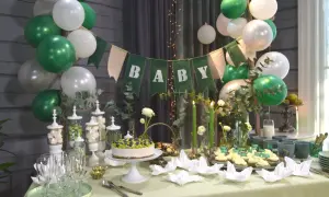 Grön och vit baby shower-dekoration med ballonger, en "BABY"-banderoll, tårta, cupcakes och godis.