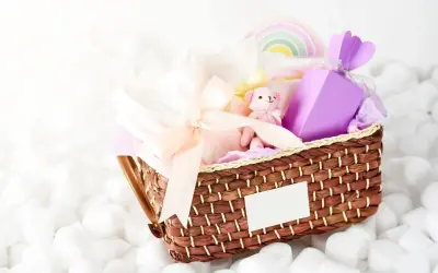 En fin presentkorg med en mjuk nalle, kläder och en lila ask. Perfekt som babybox från Kronans Apotek.