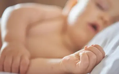 Ett litet barn sover lugnt på en vit kudde. Drömmer om att få bebis att sova hela natten.