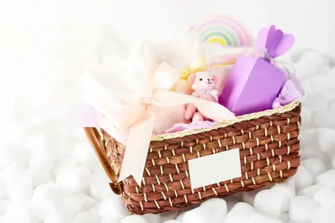 En fin presentkorg med en mjuk nalle, kläder och en lila ask. Perfekt som babybox från Kronans Apotek.
