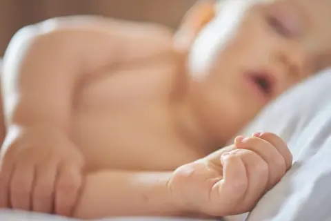 Ett litet barn sover lugnt på en vit kudde. Drömmer om att få bebis att sova hela natten.