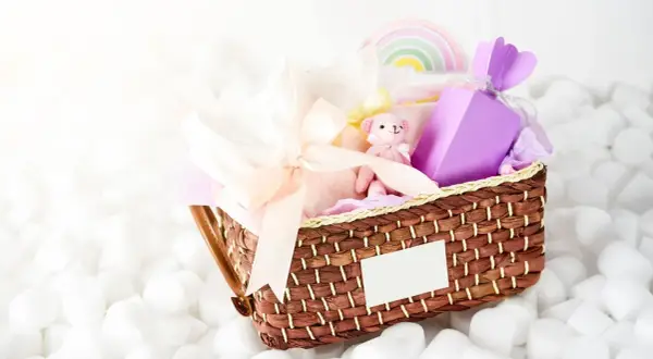 En fin presentkorg med en mjuk nalle, kläder och en lila ask. Perfekt som babybox från Kronans Apotek.