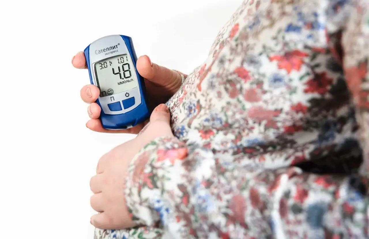 Gravid kvinna kontrollerar sitt blodsocker med en glukosmätare. En viktig del av att hantera graviditetsdiabetes.