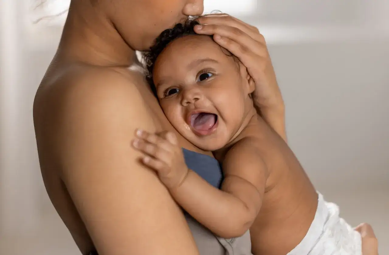 En mamma tröstar sitt barn som vaknar och skriker hysteriskt. Barnet har stora ögon och munnen öppen.