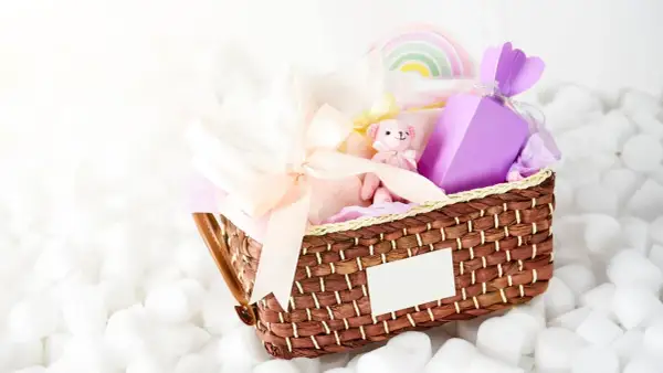 En fin presentkorg med en mjuk nalle, kläder och en lila ask. Perfekt som babybox från Kronans Apotek.
