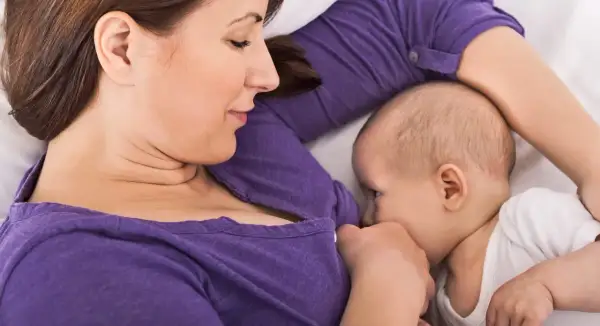 En mamma ammar sitt barn i en liggande position, en av många olika amningspositioner.