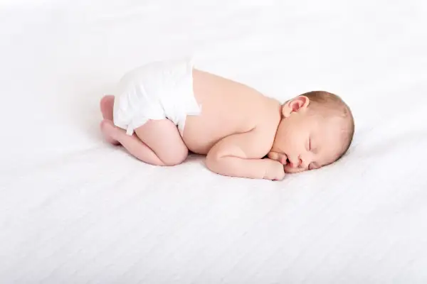 En sovande bebis i blöja, drömmer sött. Kanske undrar du hur mycket sover en 3 månaders bebis? Denna lilla sover djupt.